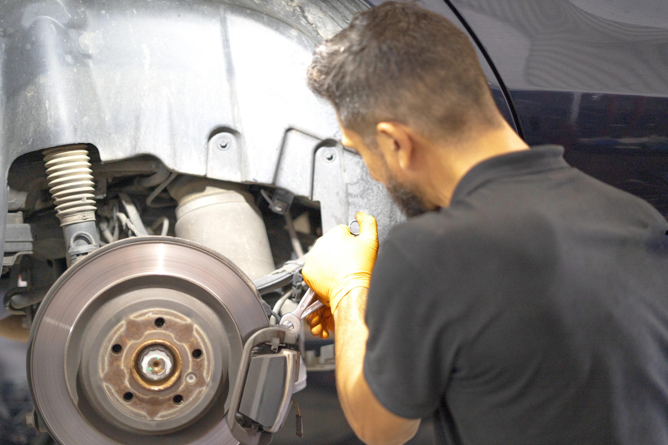 Automotive mechanic works carefully on car brake repair